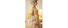 Femme portant la robe de prestige Marie-Antoinette, Souveraine de Trianon jaune et or, boutique de location Be Happy.